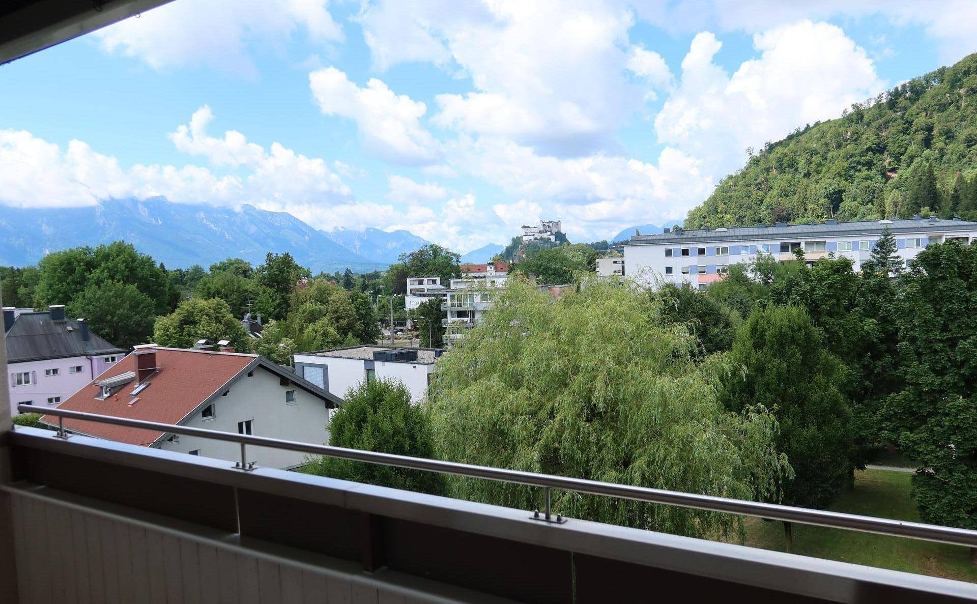 Balkon mit weitem Blick auf die umliegende Berglandschaft und grüne Umgebung.