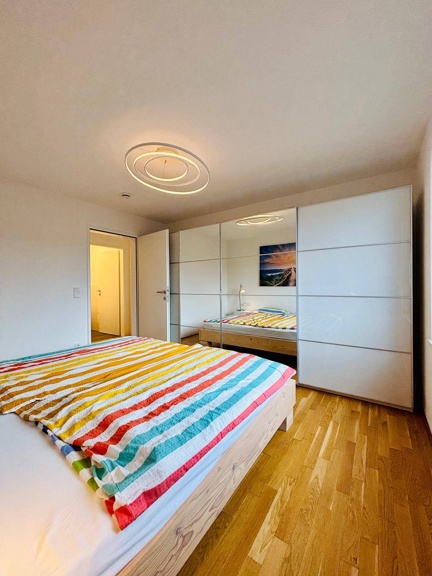 Schlafzimmer mit Holzbett und großen Spiegelschränken, die den Raum optisch vergrößern.