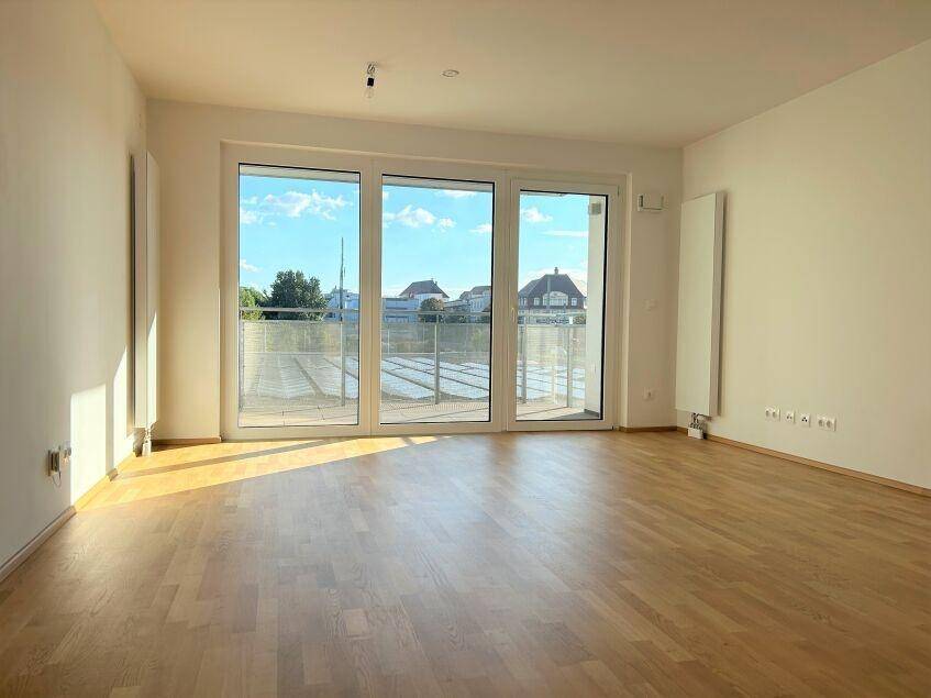 Lichtdurchflutetes Wohnzimmer mit Holzboden und Zugang zu einem sonnigen Außenbereich.