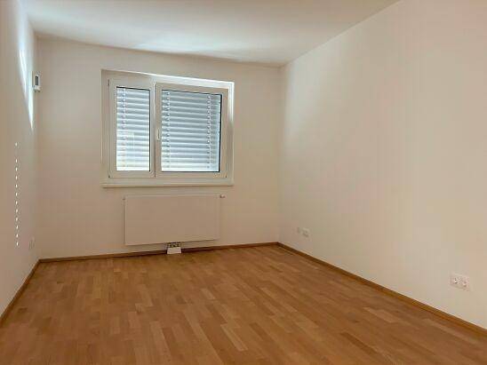 Helles Zimmer mit Holzboden und Fenster, ideal als Schlafzimmer oder Büro nutzbar.