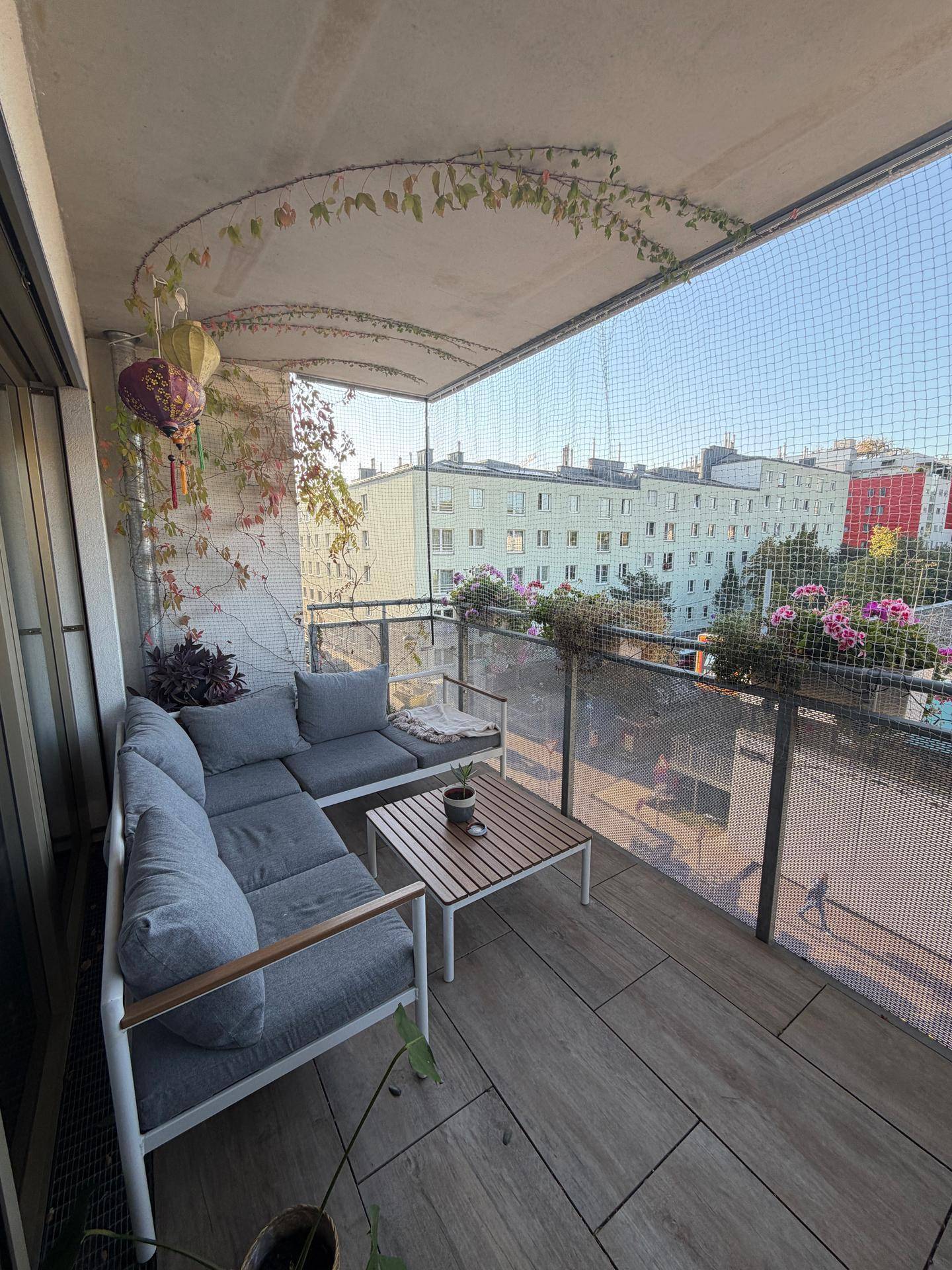 Möblierter Balkon mit Sitzgelegenheiten und Blick auf die umliegenden Gebäude der Stadt.