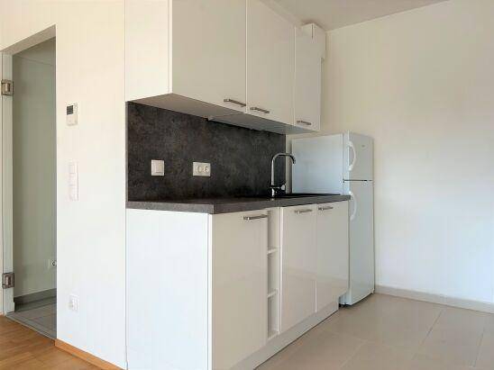Funktionale Küche mit weißen Schränken, Spüle und einem freistehenden Kühlschrank.