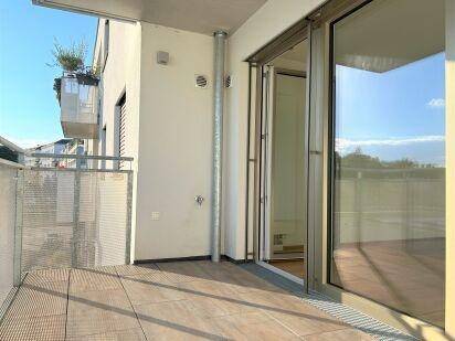 Heller Balkon mit Fliesenboden und Zugang zum Innenbereich, bietet einen Blick auf die Stadt.