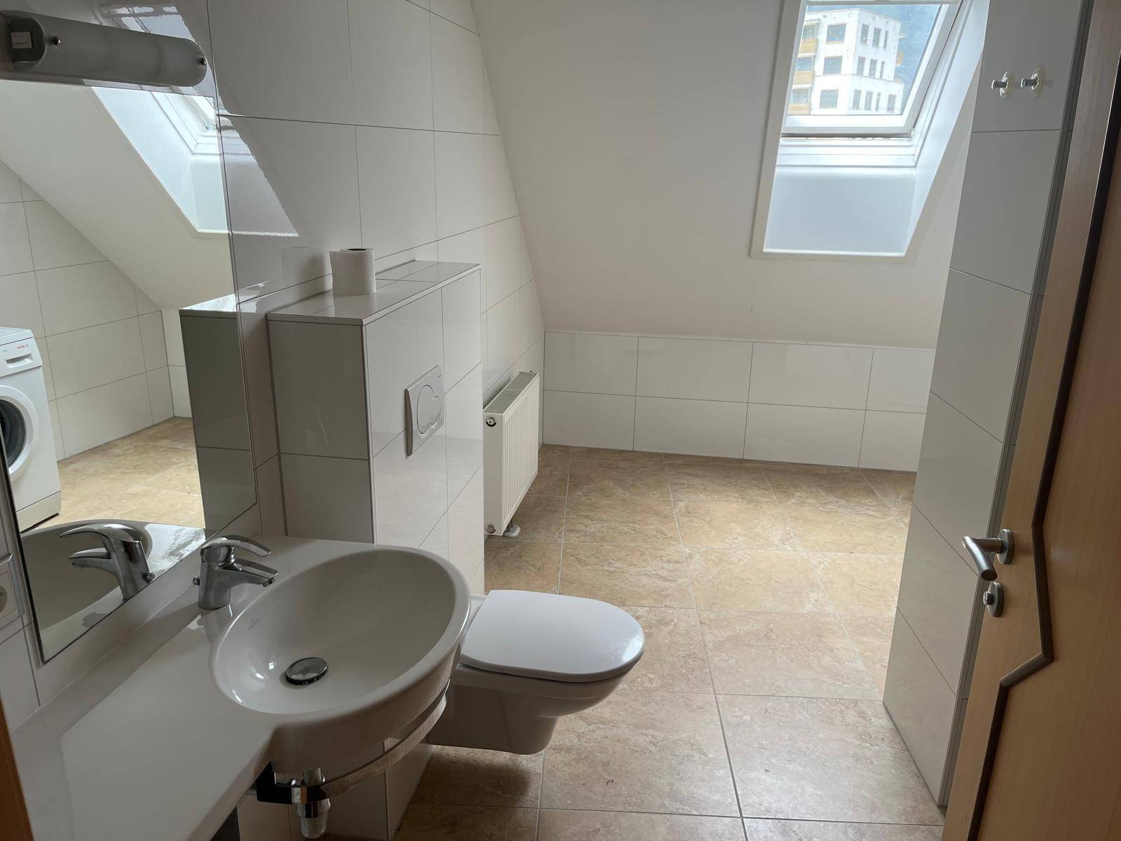 Geräumiges Badezimmer im Dachgeschoss mit Dachfenstern, WC, Waschbecken und Waschmaschinenanschluss.