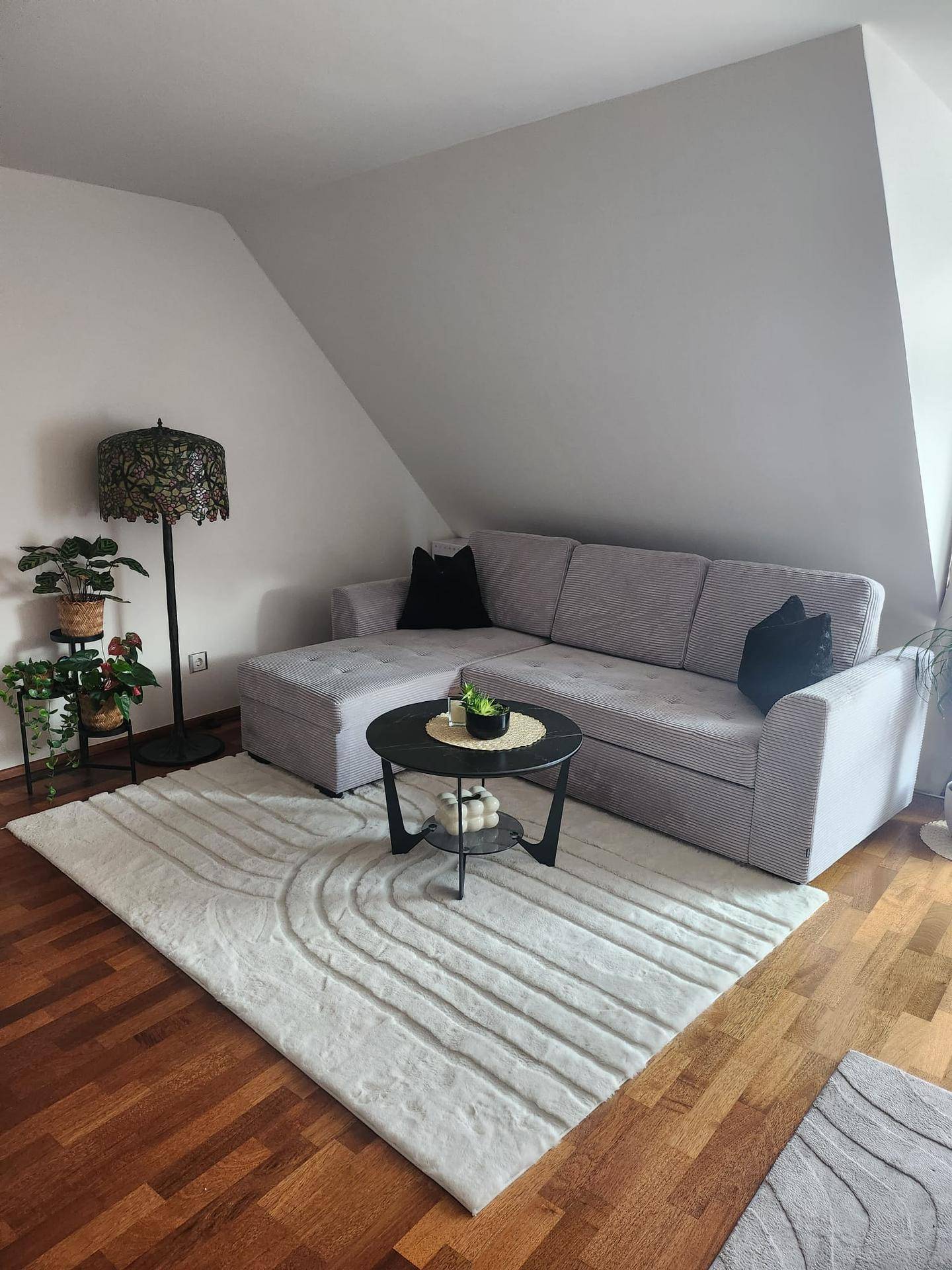 Komfortables Wohnzimmer mit Sofa, Couchtisch und Teppich, unter einer Dachschräge gelegen.