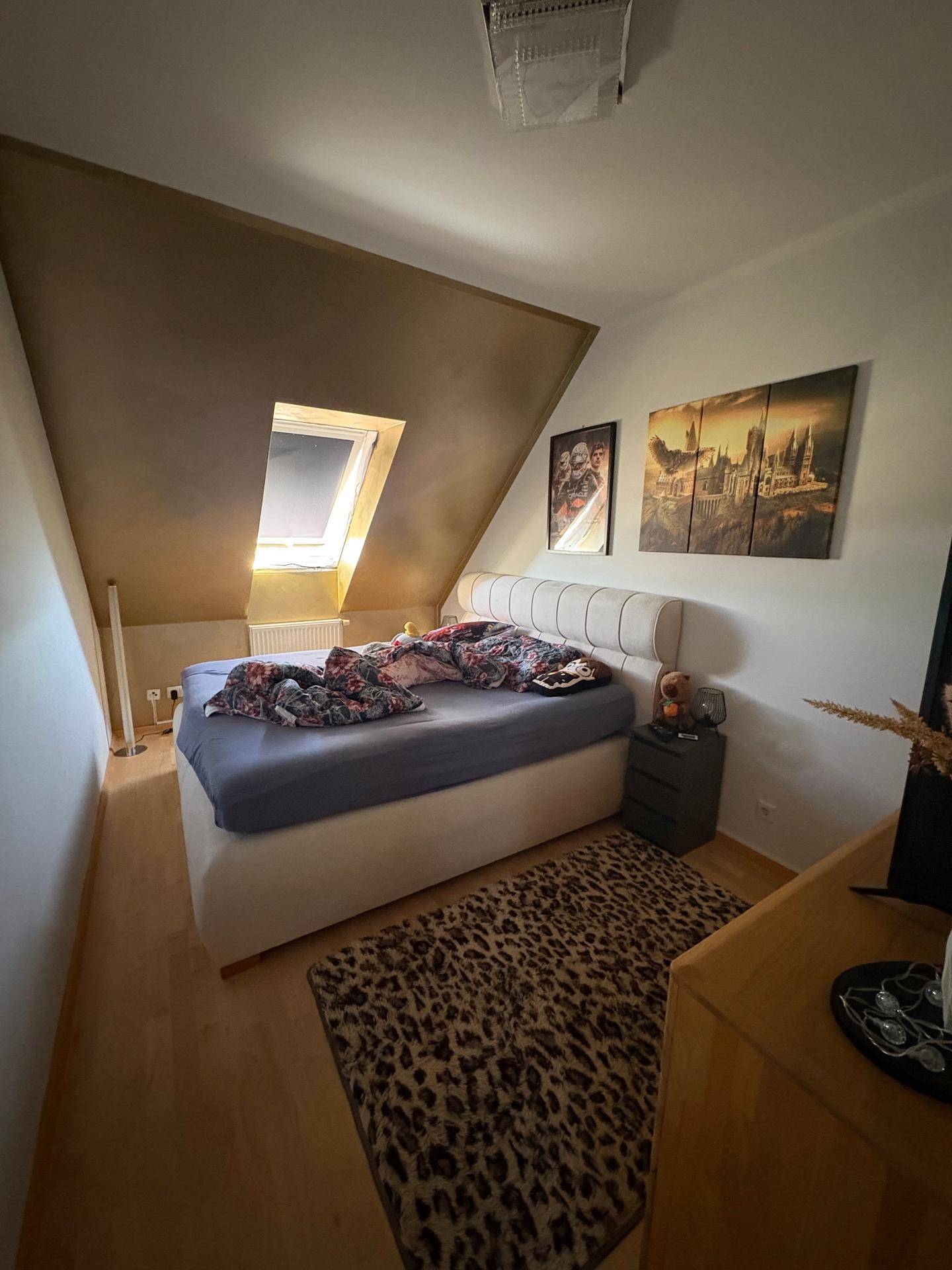 Schlafzimmer mit gemütlichem Bett, Dachschräge und Dachfenster für viel Tageslicht.
