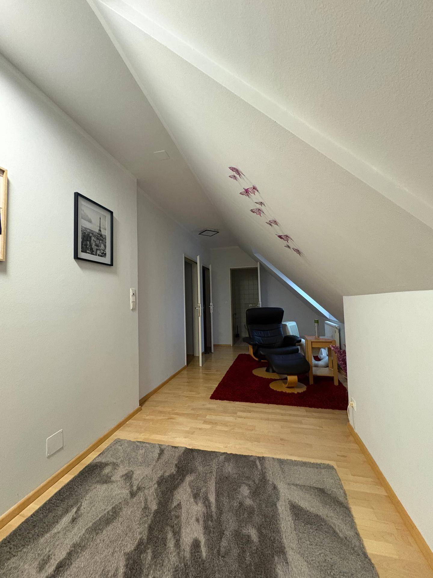 Heller Flur mit Holzboden, Dachschräge und Zugang zu weiteren Räumen.