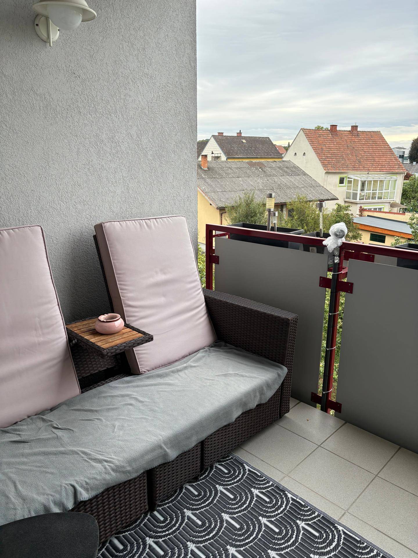 Gemütlicher Balkon mit Outdoor-Sitzgelegenheiten und Blick auf die umliegenden Häuser.