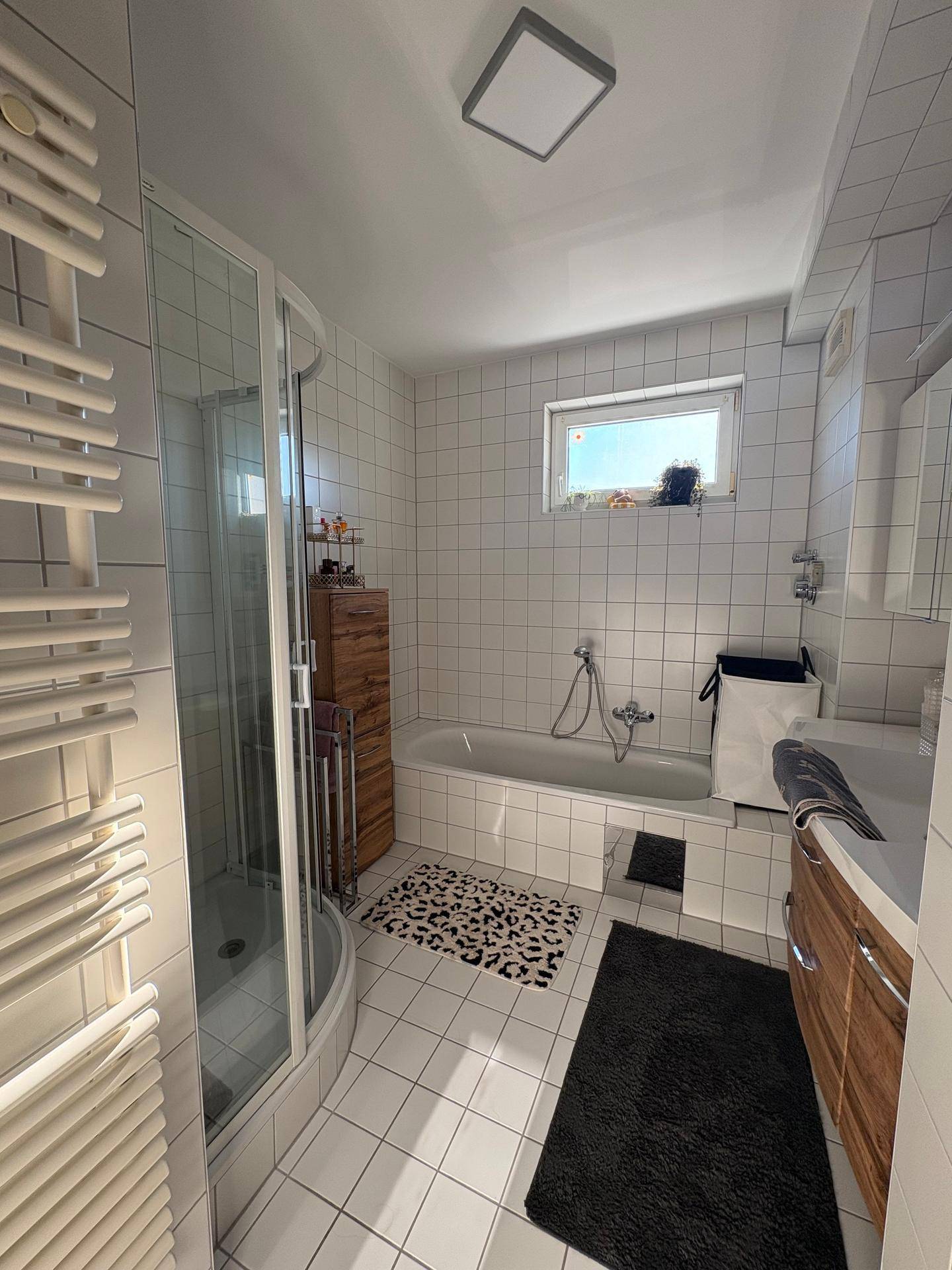 Modernes Badezimmer mit Badewanne, Duschkabine, Holzwaschtisch und beheiztem Handtuchhalter.