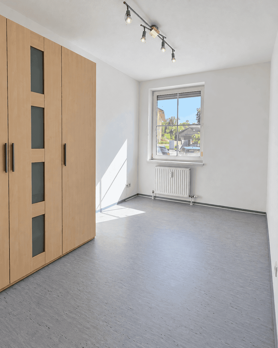 Geräumiges Schlafzimmer mit großem Kleiderschrank und grauem Vinylboden.