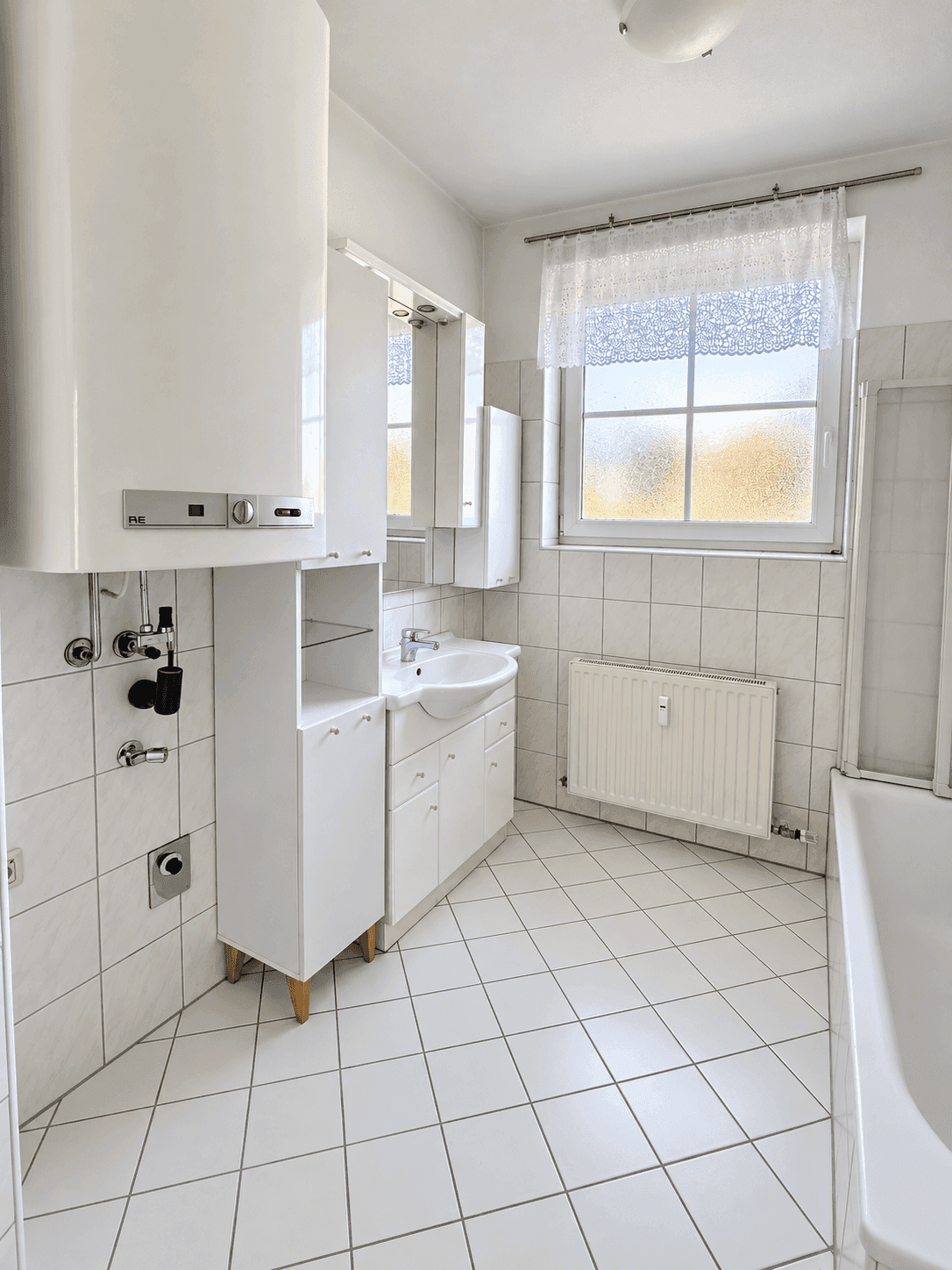 Funktionales Badezimmer mit Badewanne, Waschbecken und Fenster.