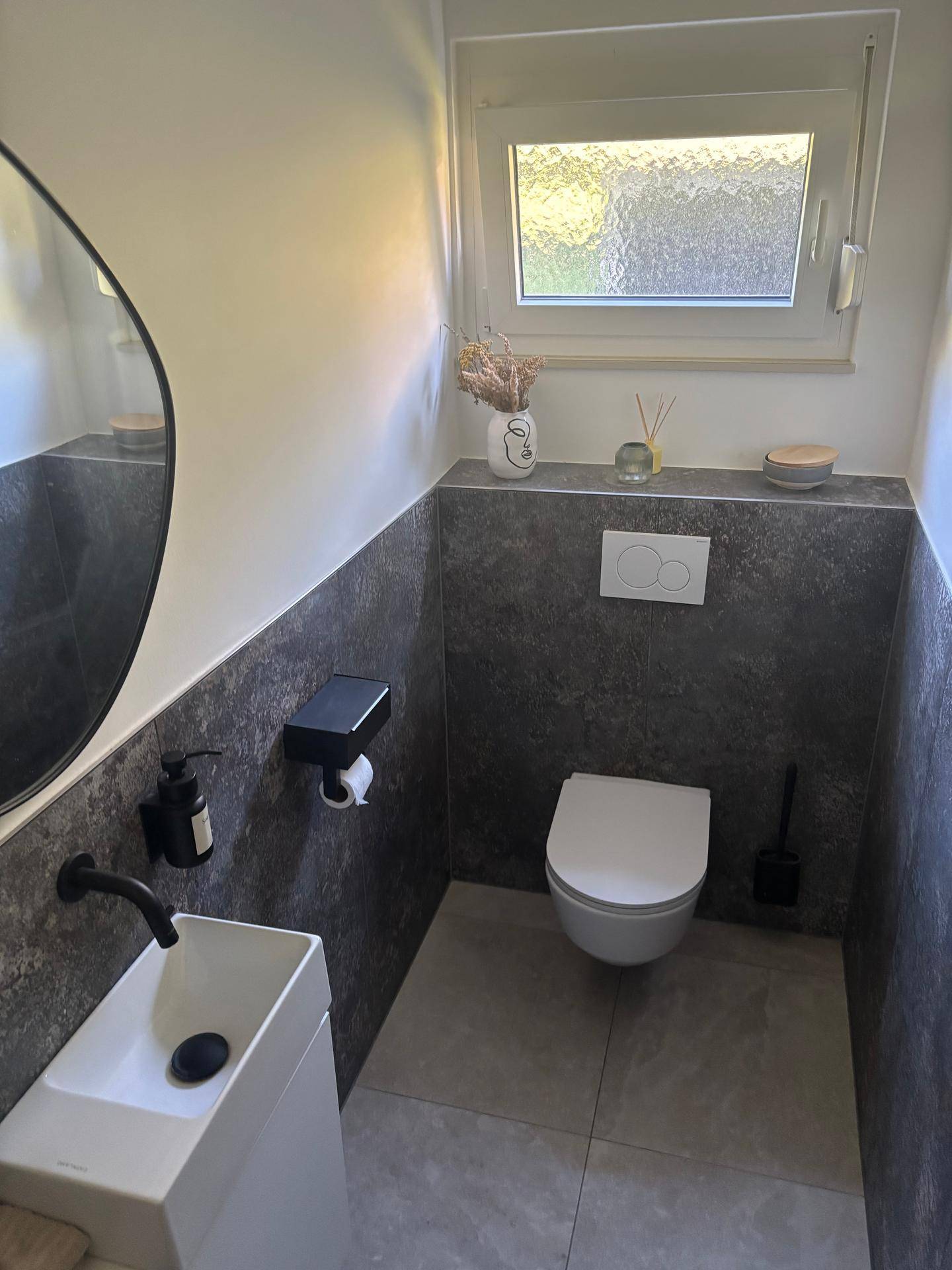 Modernes Gäste-WC mit wandhängendem WC, kleinem Waschbecken und Fenster.