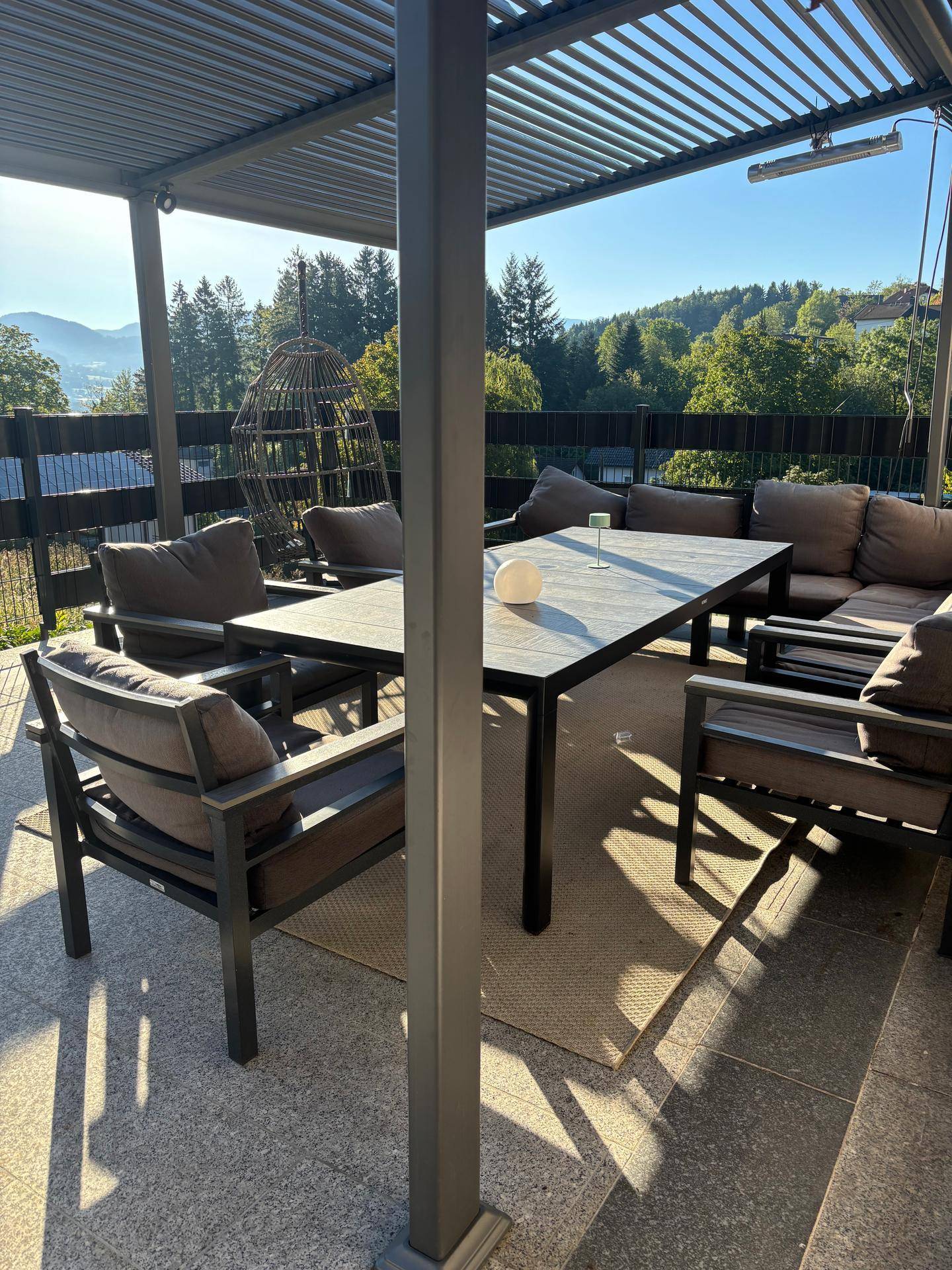 Große überdachte Terrasse mit Esstisch, Lounge-Möbeln und Bergblick.