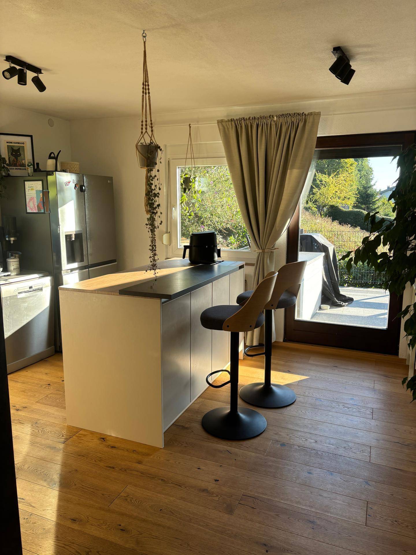Moderne Küche mit Kücheninsel, Barhockern und direktem Zugang zur Terrasse.