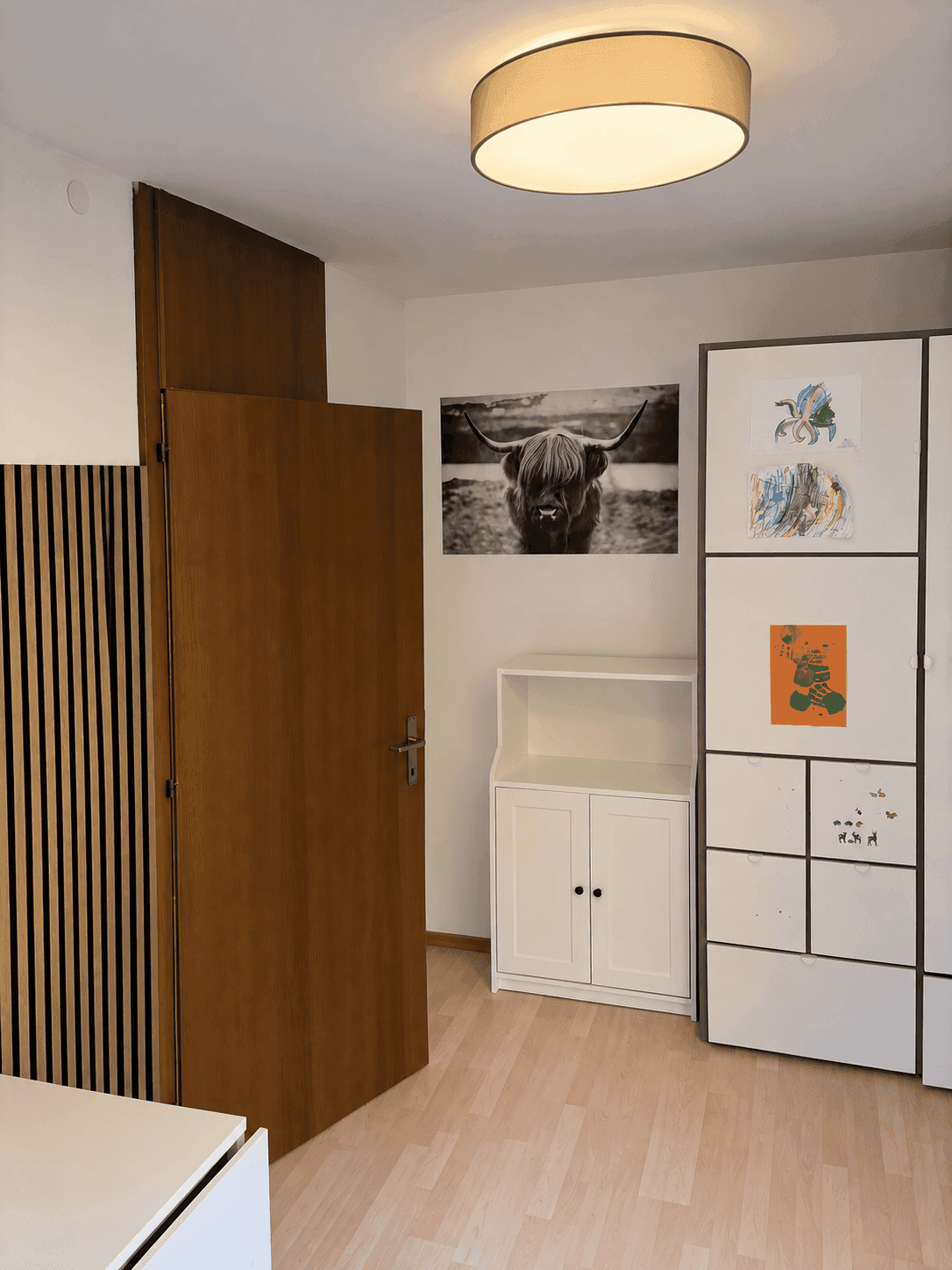 Schlafzimmer mit hellem Laminatboden und weißem Schrank.
