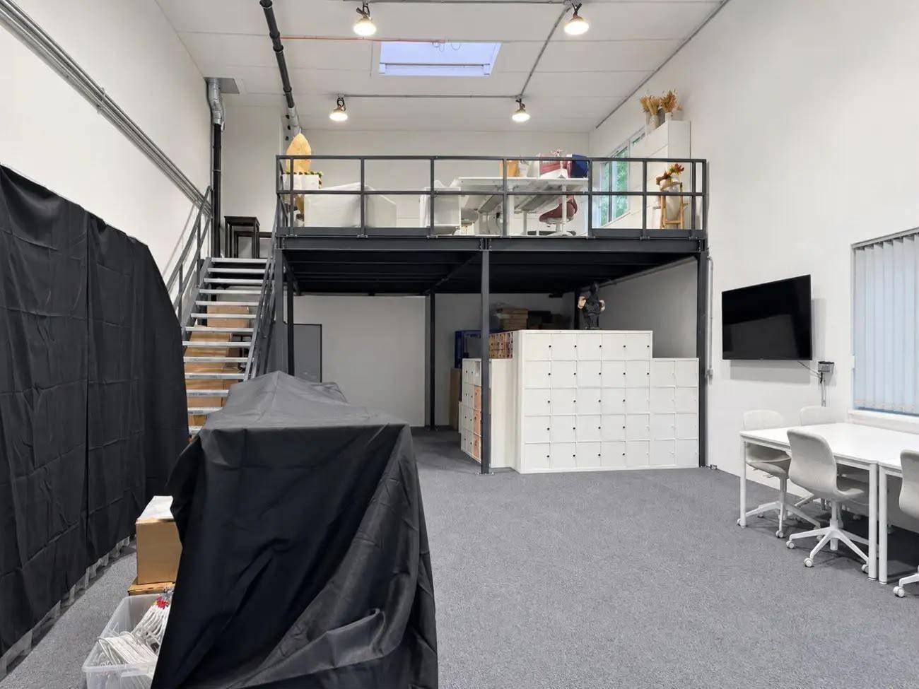 Heller, offener Bürobereich mit Galerie, Teppichboden und einem großen Tisch für Besprechungen.