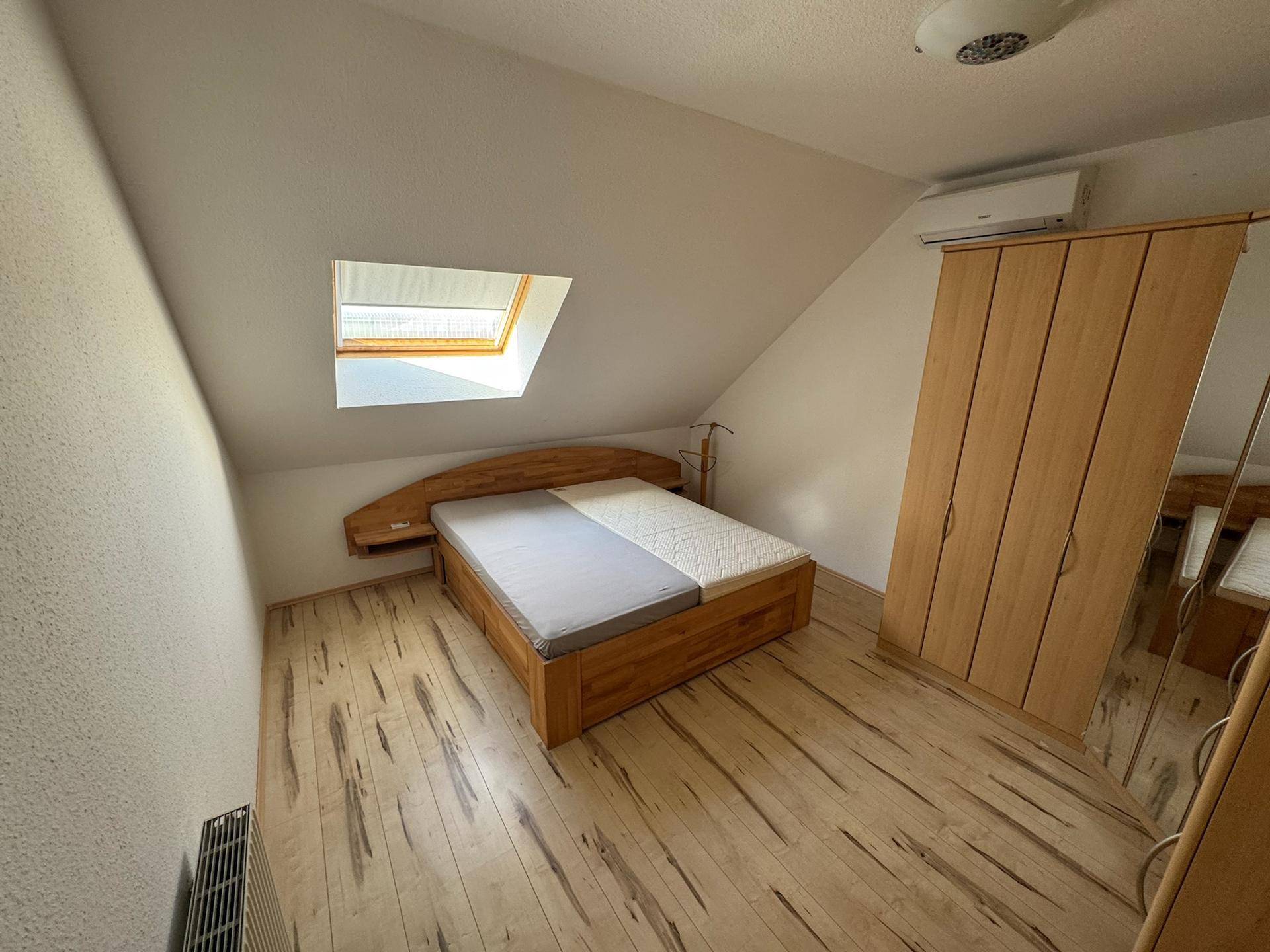 Gemütliches Schlafzimmer mit Holzboden, Dachfenster und Einbauschrank.