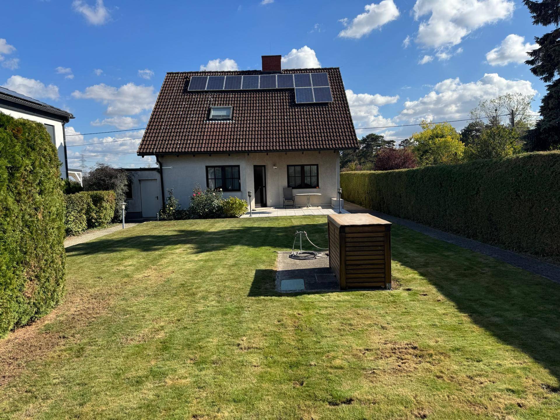 Großer, gepflegter Rasenbereich im Garten hinter dem Haus mit Solaranlage auf dem Dach.