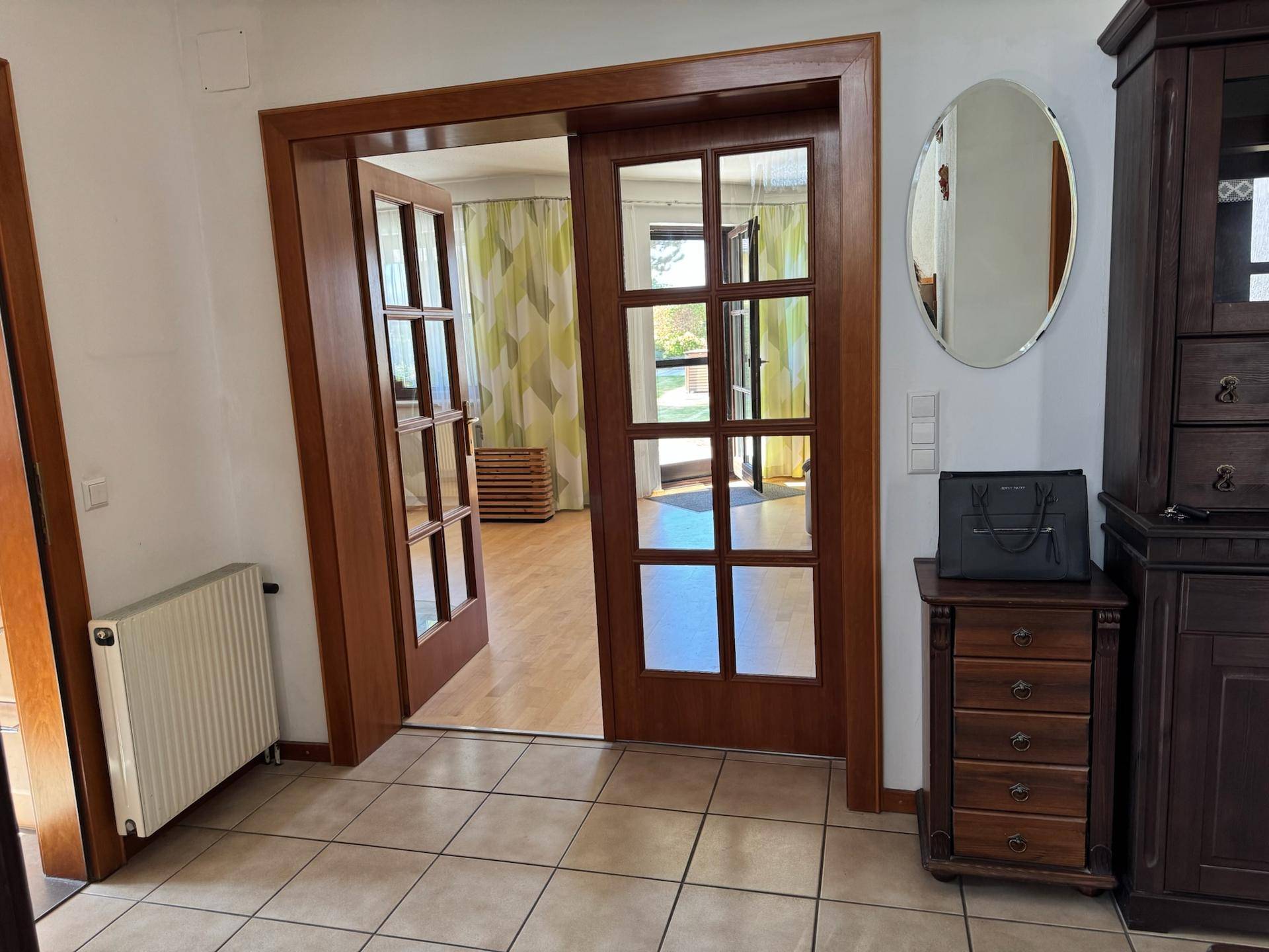 Eingangsbereich mit Fliesenboden, Spiegelschrank und Holztüren zu den angrenzenden Zimmern.