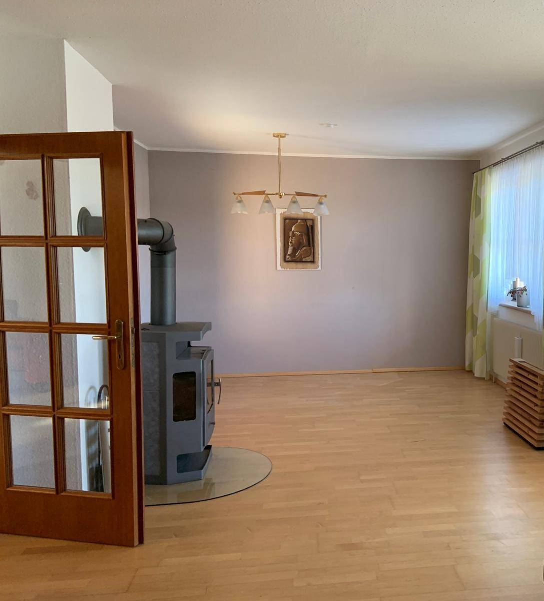 Geräumiges Wohnzimmer mit Holzboden und modernem Holzofen als gemütliche Wärmequelle.