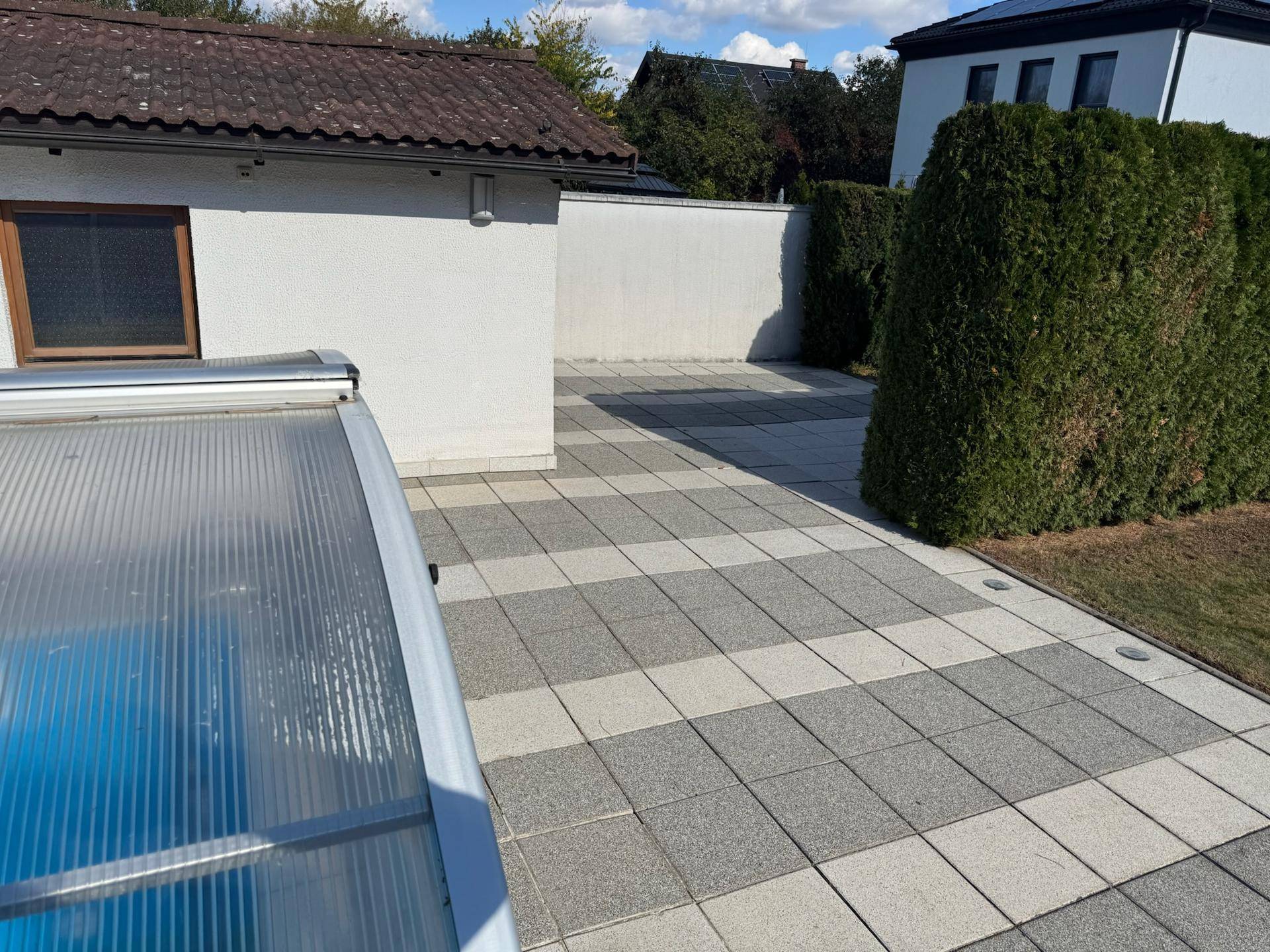 Weitläufige gepflasterte Fläche neben dem Haus und dem Poolbereich, ideal für Entspannung.