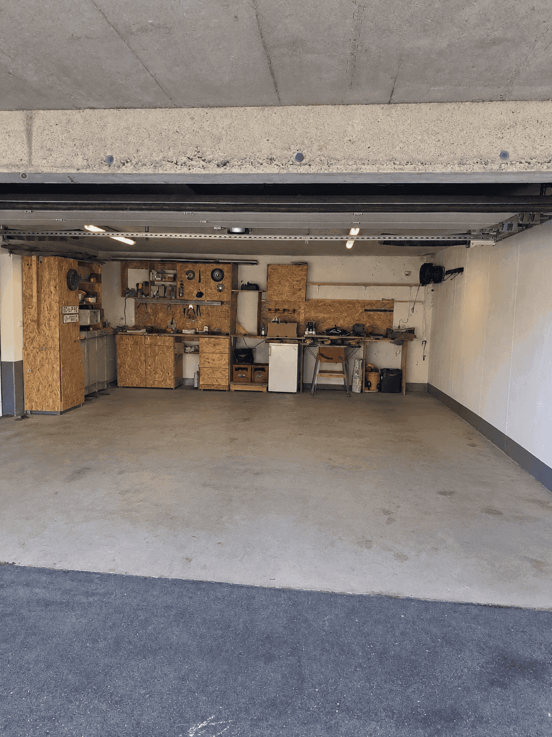 Geräumige Garage mit Werkstattbereich, Regalen und viel Platz für Fahrzeuge und Hobby.
