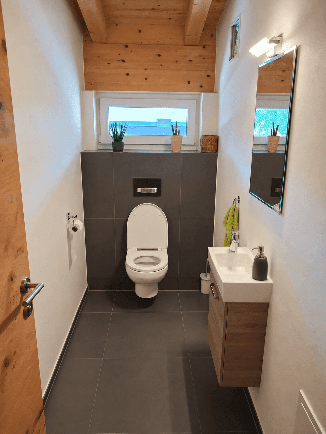 Modernes Gäste-WC mit wandhängender Toilette, Waschbecken und Fenster.