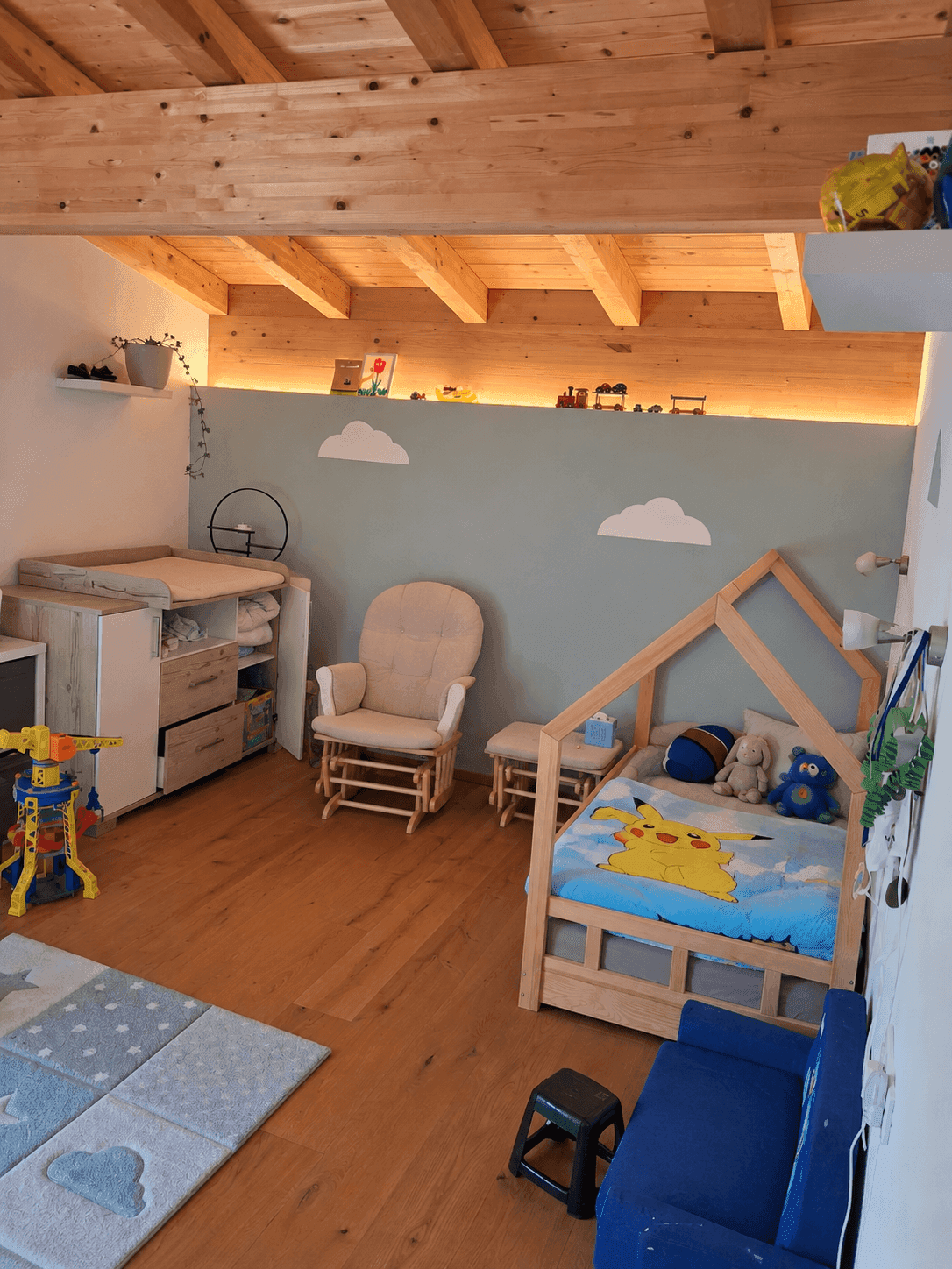 Kinderzimmer mit Holzbalkendecke, Kinderbett und spielerischer Wandgestaltung.