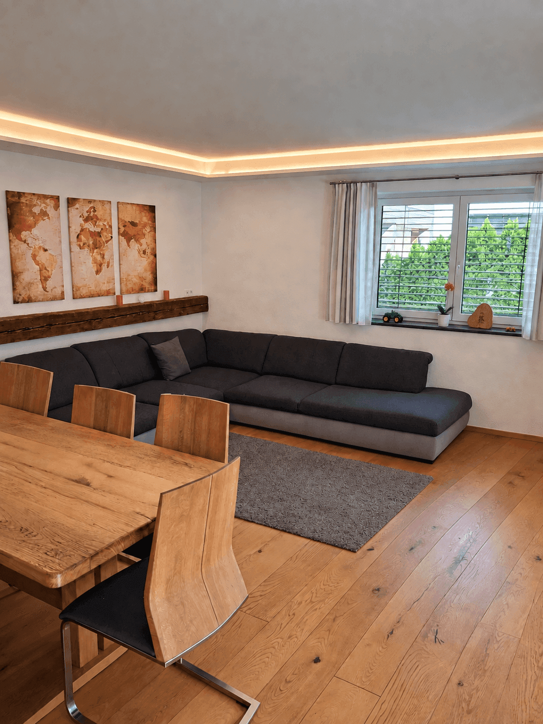 Heller Wohn- und Essbereich mit Holztisch, Ecksofa und Blick ins Grüne.