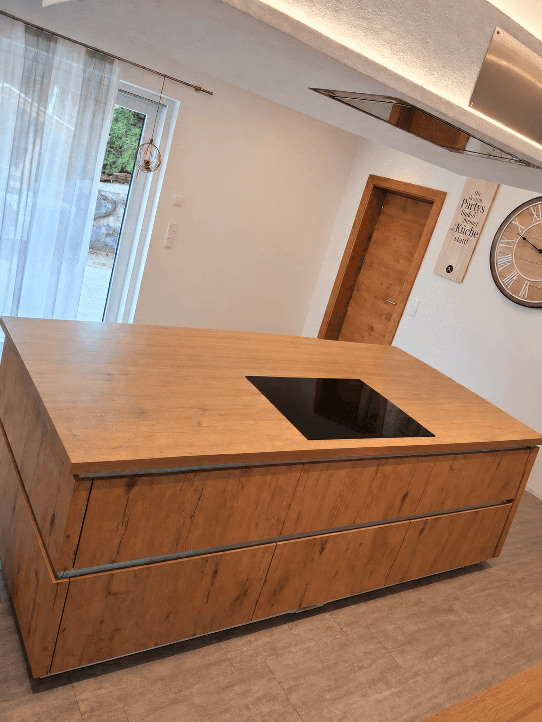 Moderne Kücheninsel mit Holzoptik-Arbeitsplatte und integriertem Induktionskochfeld.