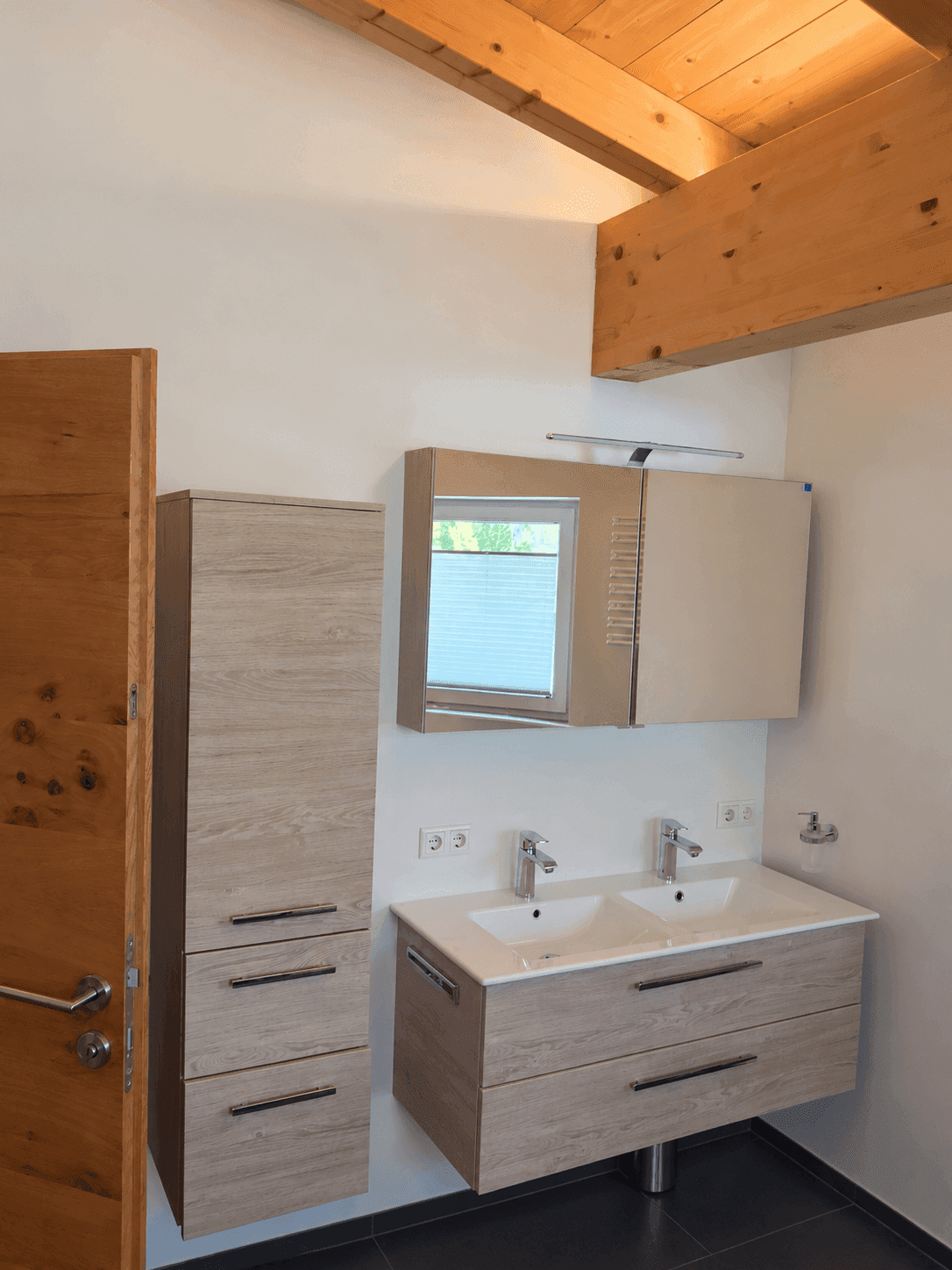 Modernes Badezimmer mit Doppelwaschbecken, Spiegelschrank und Holzbalkendecke.