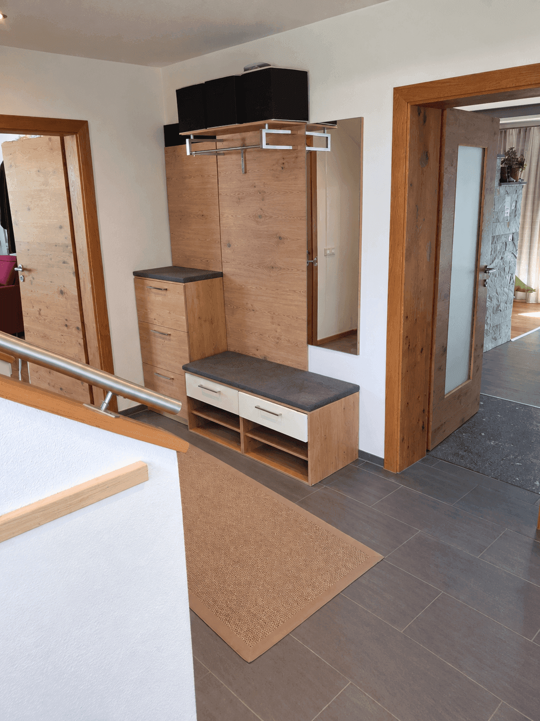 Eingangsbereich mit Garderobe, Spiegel und Fliesenboden.