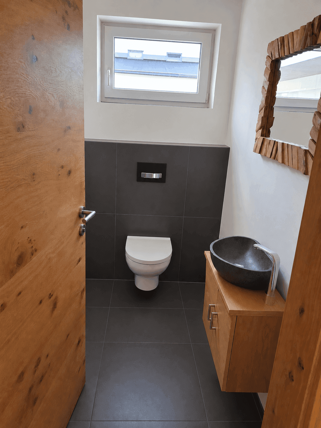 Modernes Gäste-WC mit wandhängender Toilette, einzigartigem Waschbecken und Fenster.