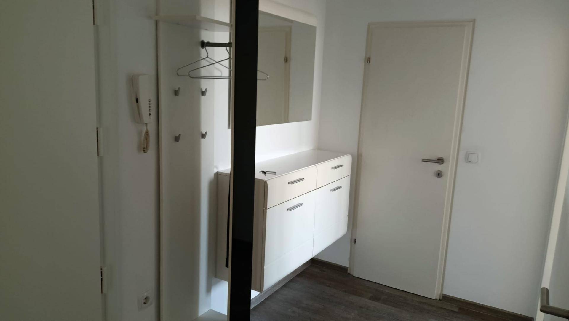 Heller Flur mit Garderobe, Spiegel und praktischem Schrank, ideal für den Eingangsbereich.