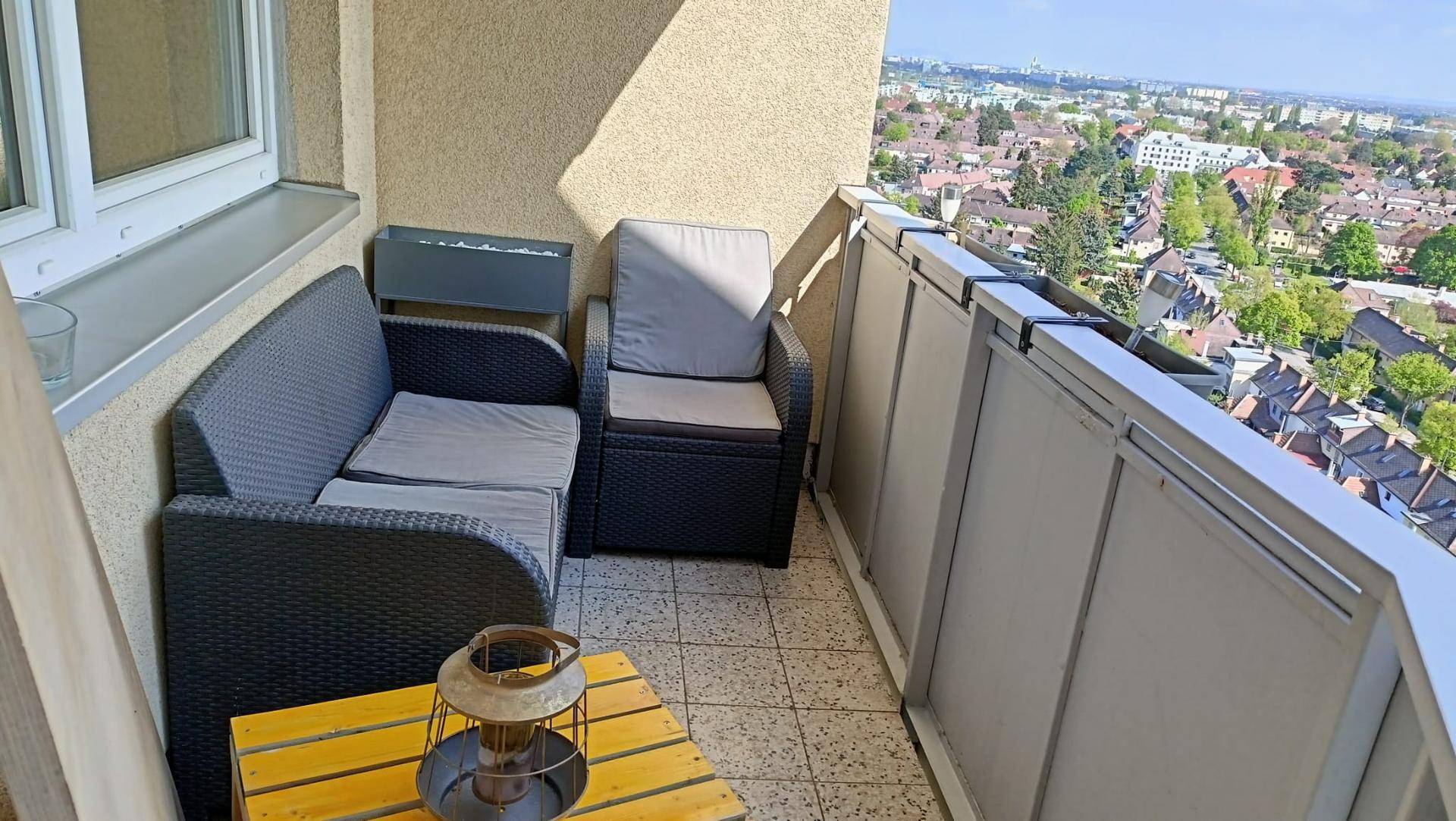 Gemütlicher Balkon mit Sitzgelegenheiten und Fliesenboden, bietet einen weiten Blick über die Stadt.