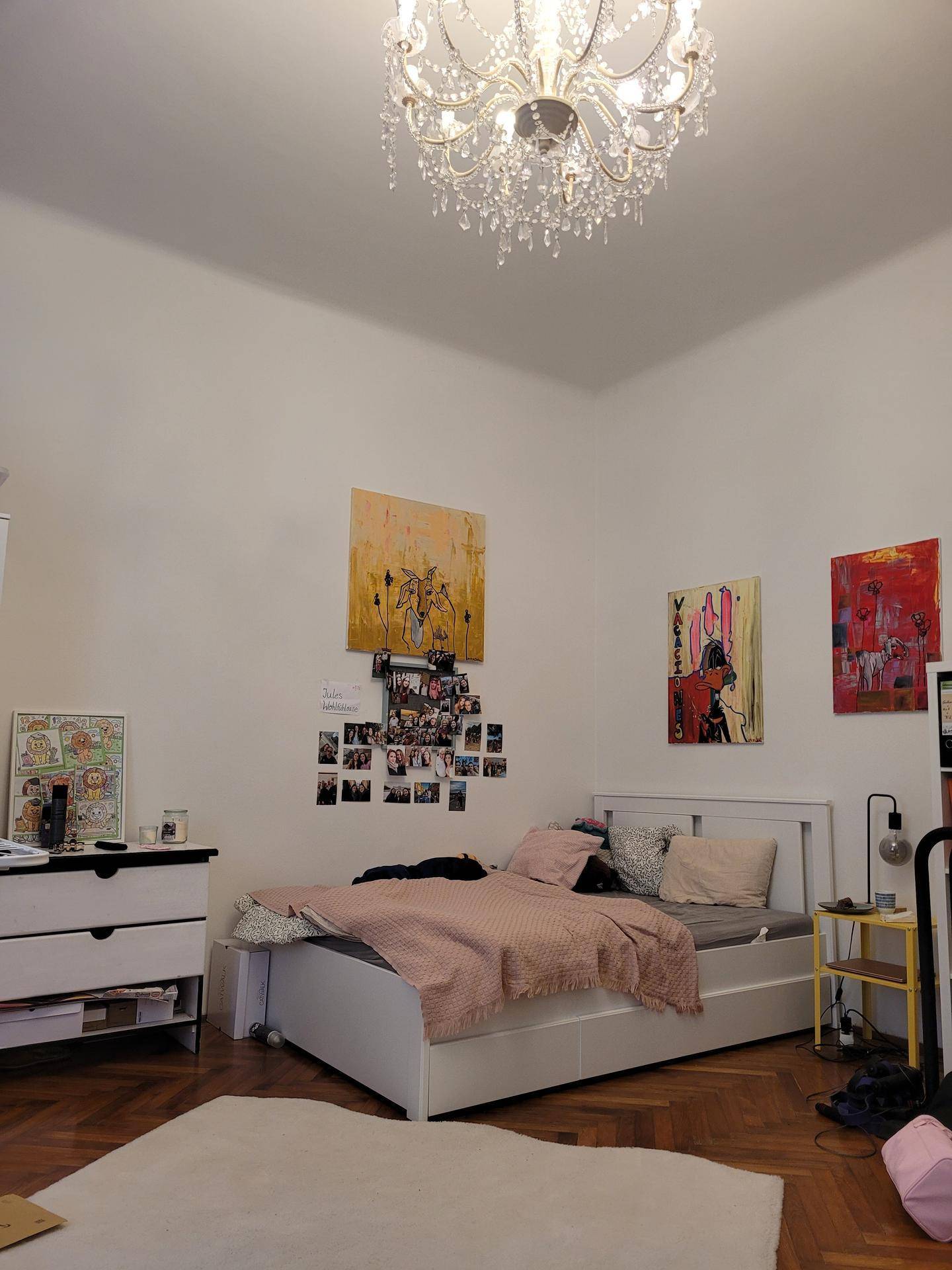 Schlafzimmer mit Doppelbett, Kommode und Kunstwerken, ausgestattet mit klassischem Parkettboden.