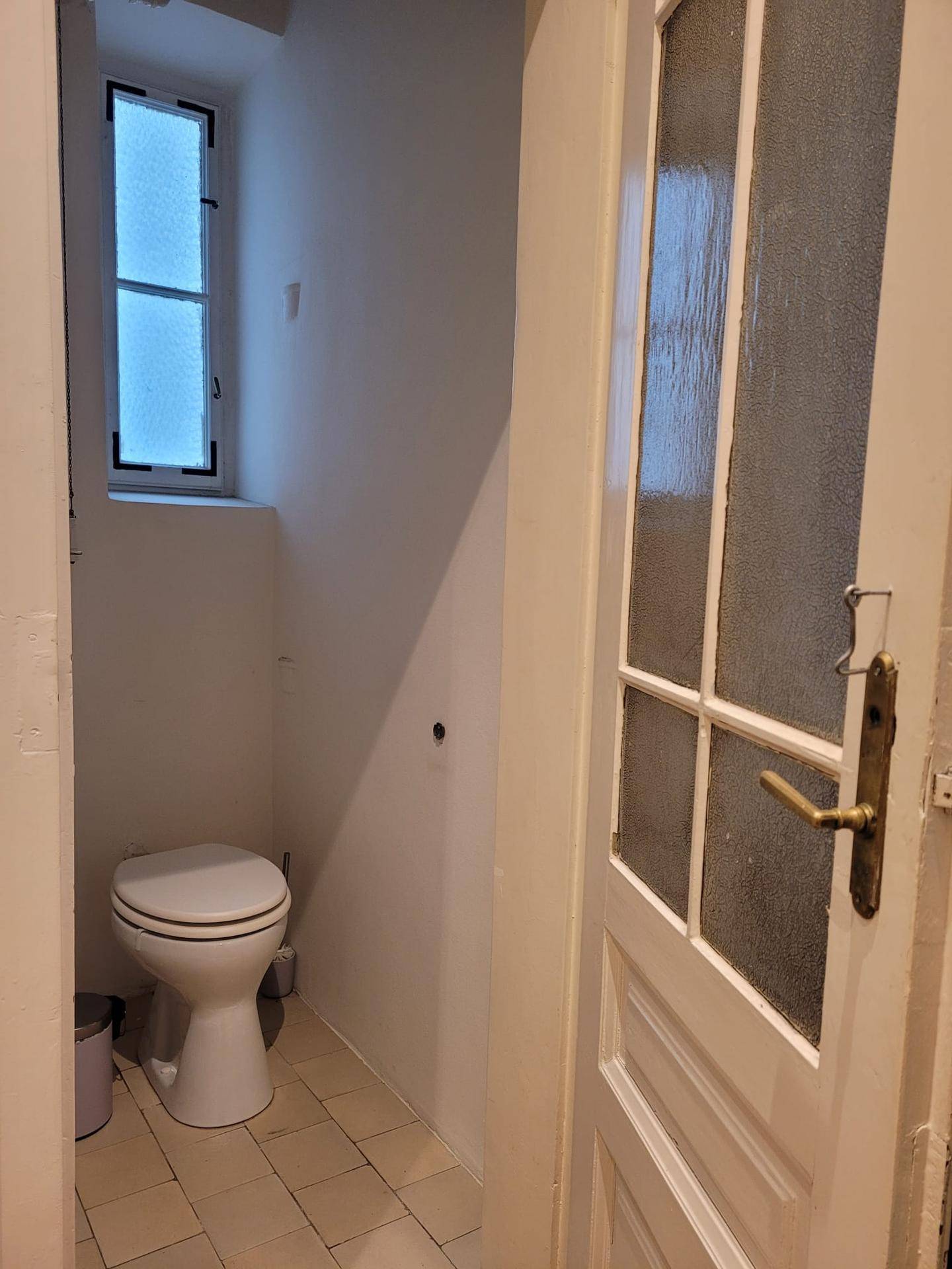 Kleines Gäste-WC mit Toilette und einem Fenster, das für natürliche Belüftung sorgt.