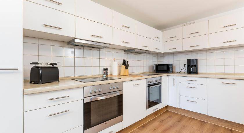 Moderne Einbauküche mit weißen Schränken, Induktionskochfeld, Backofen und Mikrowelle.