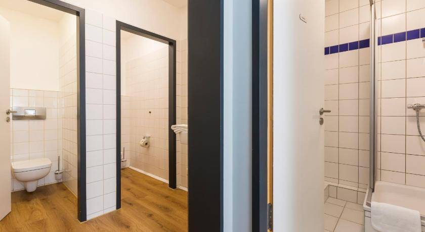 Funktionales Badezimmer mit separater Toilette und Duschbereich, gefliest und mit Holzfußboden.