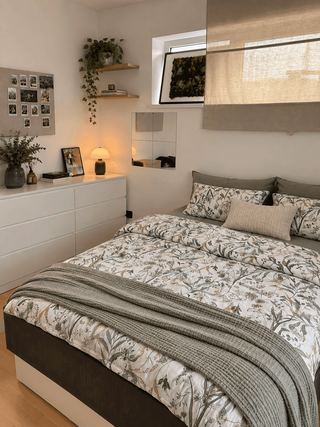Helles Schlafzimmer mit bequemem Bett, weißer Kommode und floral gemusterter Bettwäsche, gemütlich eingerichtet.