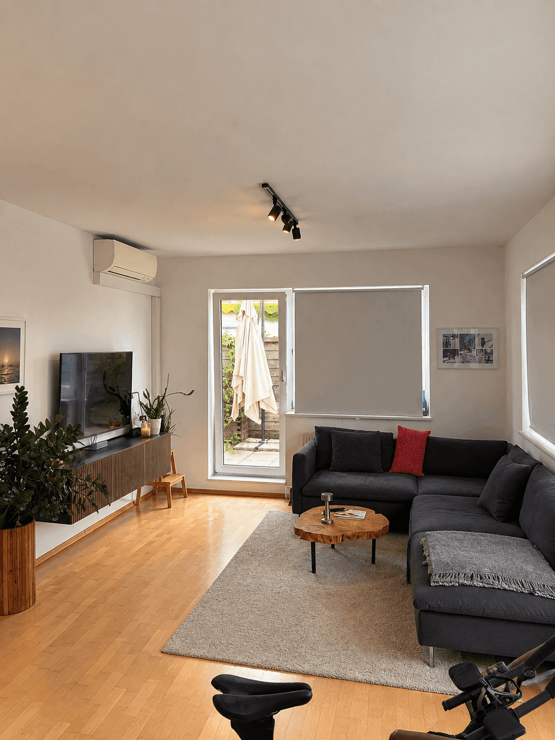 Gemütliches Wohnzimmer mit großem Sofa, Holztisch und Zugang zu einem Außenbereich, ausgestattet mit Klimaanlage.