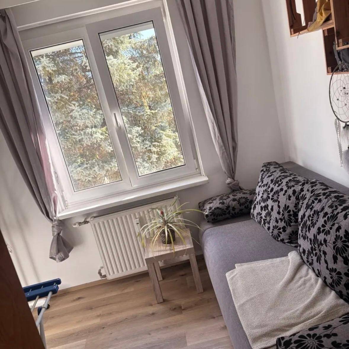 Kleiner Raum mit Sofa, Fenster und Blick auf Bäume, ideal als Arbeits- oder Gästezimmer.