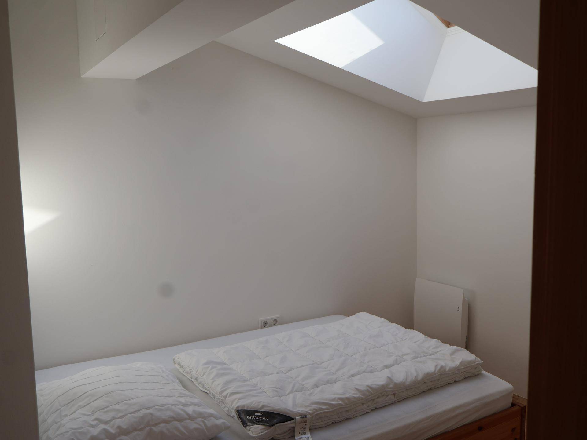 Gemütliches Schlafzimmer mit Holzboden und einem großen Dachfenster für viel Licht.
