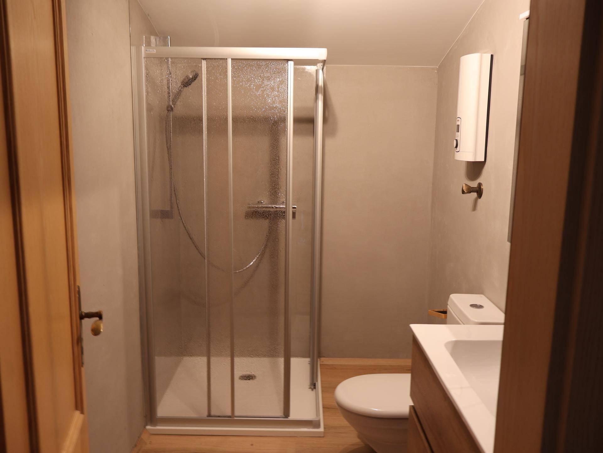 Kleines Badezimmer mit Duschkabine, WC und Waschbecken, funktional eingerichtet.