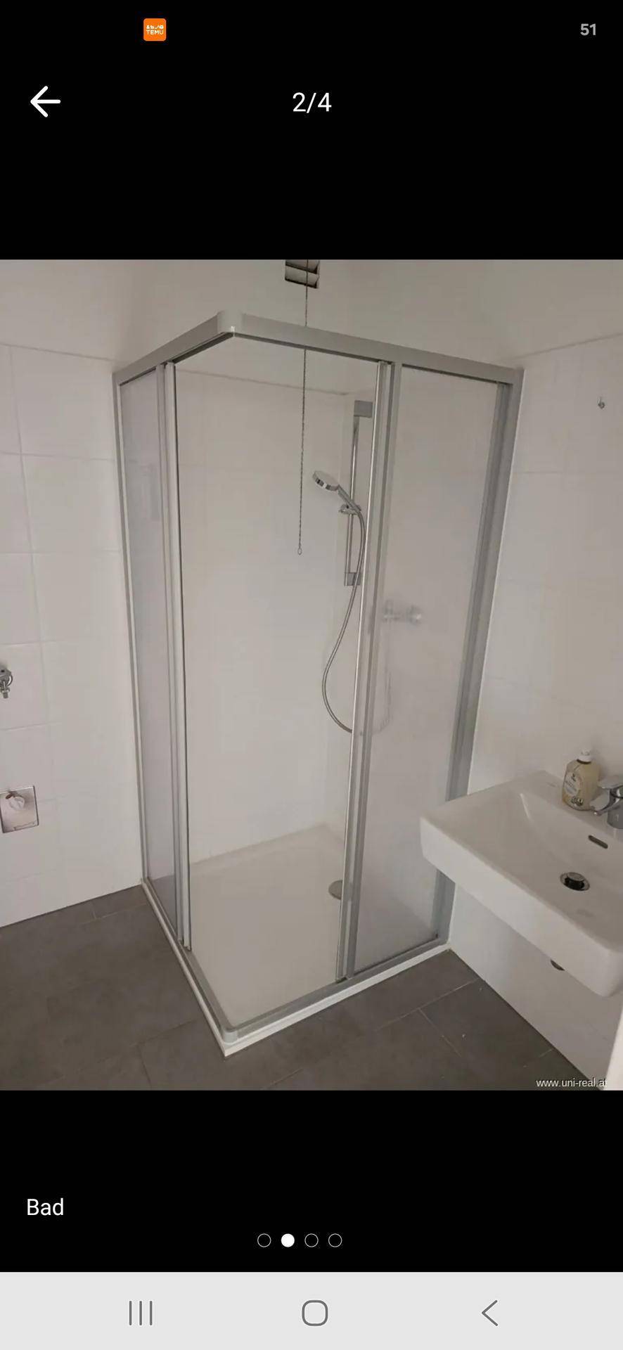 Modernes Badezimmer mit Duschkabine, Waschbecken und hellen Fliesen an den Wänden.