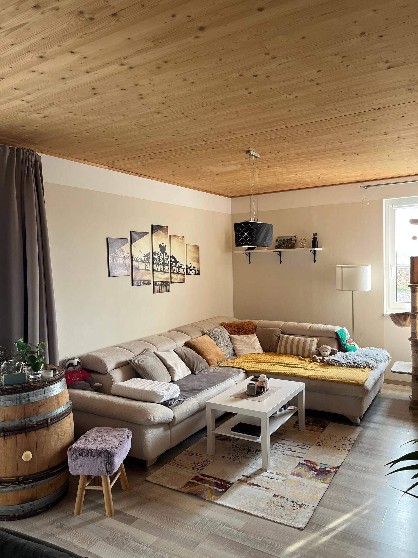 Gemütliches Wohnzimmer mit großem Ecksofa, Holzdecke und Laminatboden.