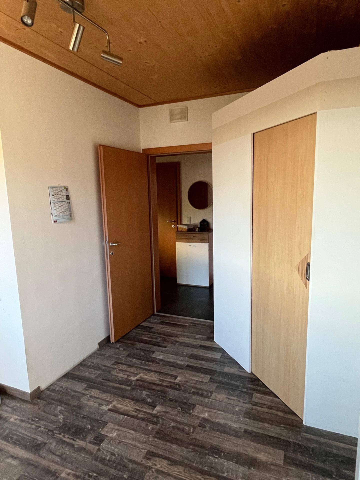 Übergangsbereich mit Holzdecke und Laminatboden, der zu weiteren Räumen führt.
