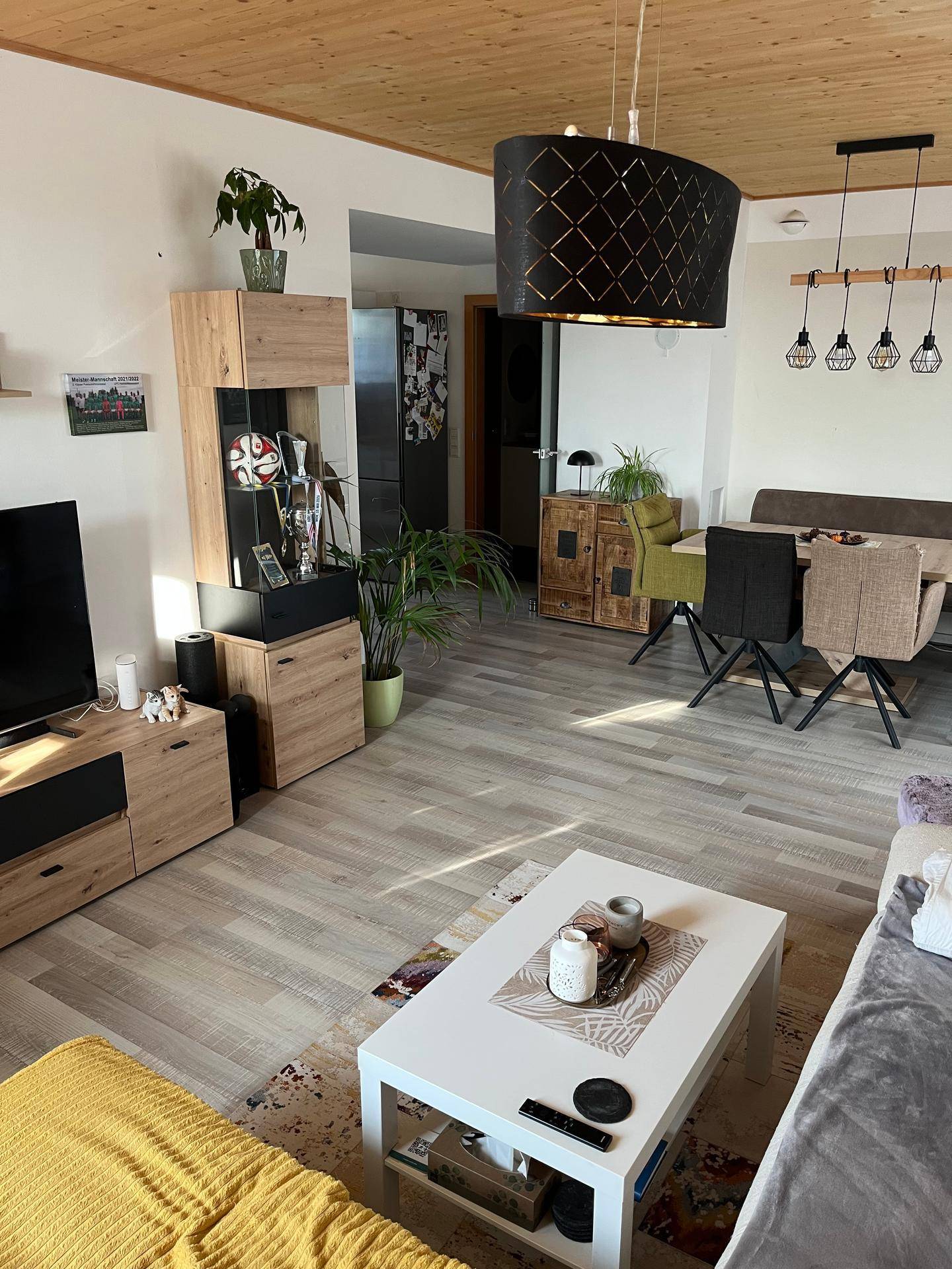 Offener Wohn- und Essbereich mit Holzdecke, Laminatboden und moderner Einrichtung.