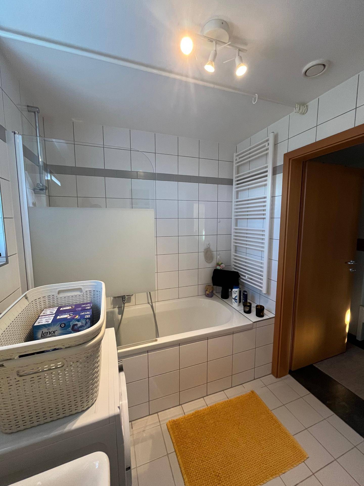 Badezimmer mit Badewanne, Duschabtrennung und beheiztem Handtuchhalter.