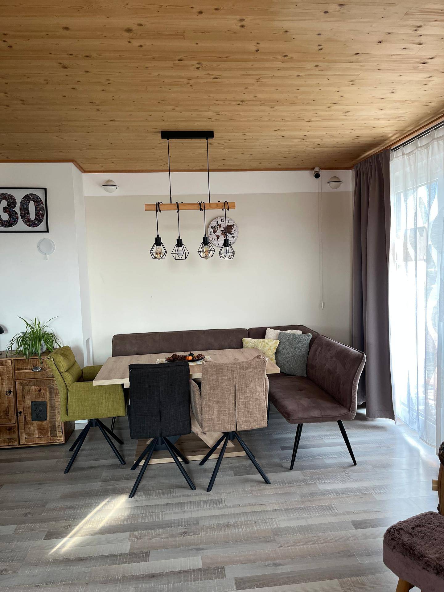 Essbereich mit Holzdecke, Laminatboden und einer modernen Sitzgruppe am Fenster.